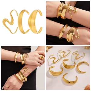 Set detallado de tres brazaletes dorados de acero inoxidable con diseños ondulados y lisos
