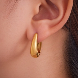 Créoles épaisses en forme de U plaquées or 18 carats portées par un mannequin femme