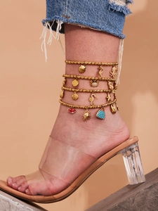 Detail of layered gold beaded anklet featuring marine charms like starfish and seahorses