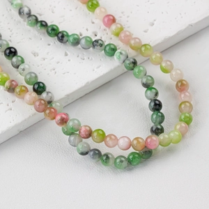 Teal and colorful natural jade beads necklace with marbled texture on white stone base