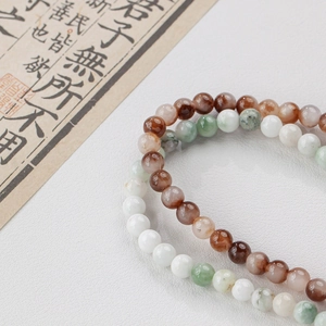 Natural round jade beads bracelets in brown and green displayed on white textured background