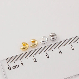 Macro view of 3-4mm 14K gold and silver crescent crimp covers for DIY jewelry making