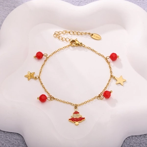 Detail of gold stainless steel bracelet with red Christmas tree and star charms
