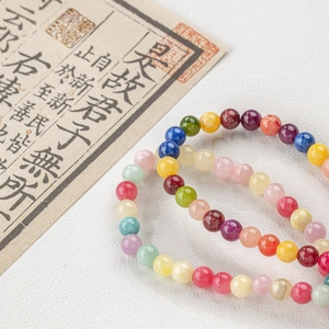 Macro shot of colorful natural jade beads on white leather with Chinese calligraphy