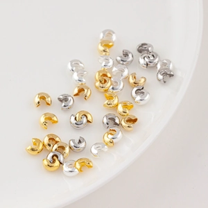 Macro detail of 14K gold and silver plated C-shaped crimp bead covers for jewelry making