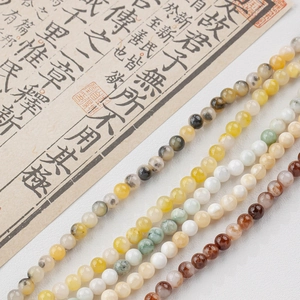 Polished natural jade beads in assorted colors arranged on a vintage scroll background