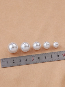 Detailed view of ABS faux pearl pendants in various sizes next to a measuring ruler