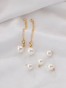Detailed view of cream ABS pearl pendants with gold star accents on soft white fabric