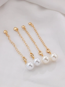 Close-up of golden extension chains with white faux pearls and star charms on silk