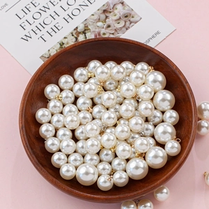 Macro detail of glossy ABS imitation pearl pendants with gold and silver metal loops