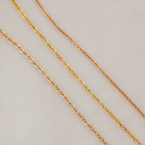 Three rows of 18K gold plated O-link chains in various thicknesses on fabric background
