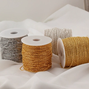 Detailed view of 1.5mm gold and silver jewelry making chains wound on white plastic spools