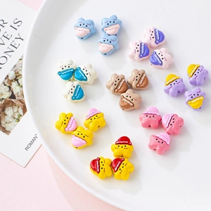 Close-up of colorful cartoon nightcap charms in a white ceramic bowl for DIY jewelry