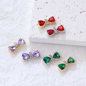 Détail macro de pendentifs nœuds en cristal en forme de cœur rouge, violet et vert émeraude