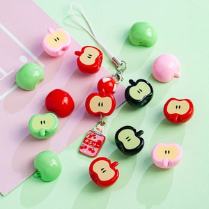 Close-up of colorful acrylic apple beads and a mini juice can charm for DIY jewelry