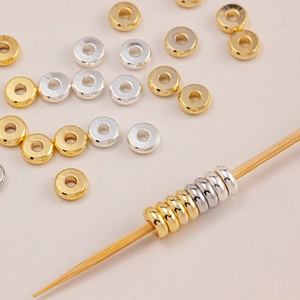 Golden and silver flat wheel spacer beads for DIY jewelry making on a light background