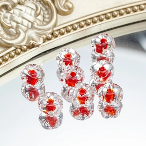 Macro detail of 12mm lampwork glass beads with red flower core on reflective surface