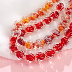 Macro detail of handmade gradient glass beads with red and orange spiral thread textures