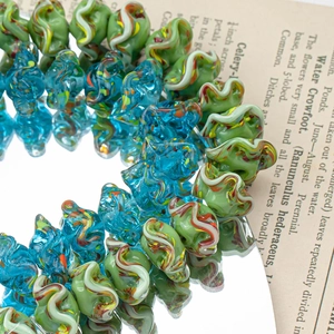 Makro-Detail von gewellten Lampwork-Glasperlen mit bunten Streifen für DIY-Schmuck