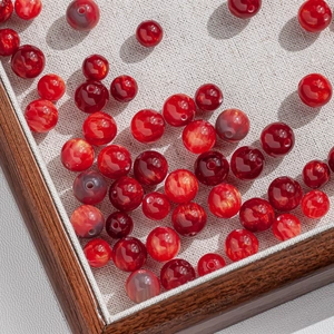 Detail of red resin beads with gold foil inside for DIY jewelry making on a tray