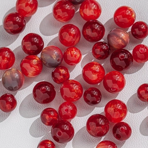 Macro shot of 8-10mm red resin beads with gold foil textures for DIY jewelry making
