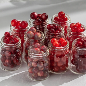 Macro shot of assorted red resin beads in glass jars for DIY jewelry making