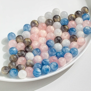 Macro detail of mixed pink and blue cat eye beads with golden glitter for DIY jewelry making