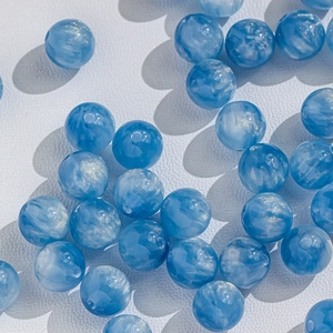 Macro detail of blue marble effect glass beads with sparkling gold stardust texture for DIY