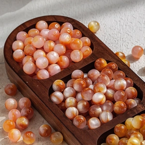 Primer plano de cuentas de ágata ojo de gato de 10 mm en naranja y rosa para joyas DIY