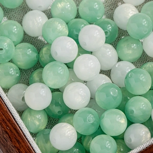 Macro shot of mint green and pearl white round beads with golden glitter for DIY jewelry