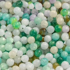 Macro detail of green and white cat-eye beads with golden glitter for DIY jewelry making