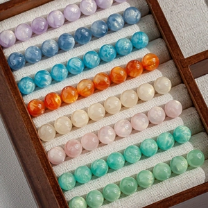 Macro shot of 8mm cat-eye beads in macaron colors on a tray for DIY jewelry
