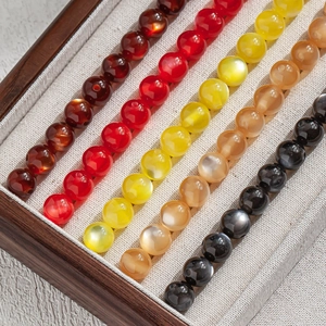 Detailed close-up of colorful 10mm resin beads with cat eye effect in a wooden tray