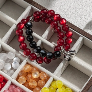 Red cat eye resin beaded bracelet with silver flower pendant in a wooden box