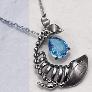 Macro shot of silver whale bone pendant with pear-cut blue gemstone on a fine chain