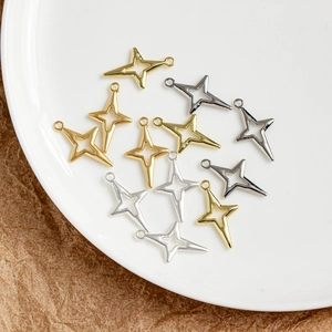 Vue macro de pendentifs étoile dorés et argentés pour bijoux DIY sur une assiette blanche