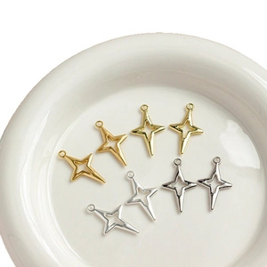 Pendentifs en forme d'étoile dorée et argentée pour création de bijoux sur plateau blanc