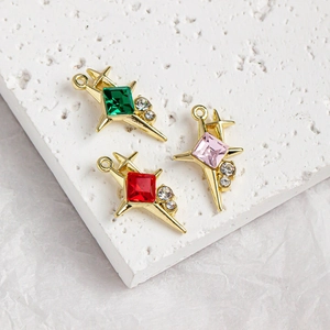 Star-shaped gold pendants with colorful square gems on white marble background