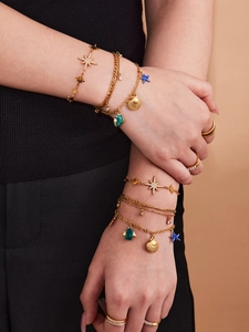 Detailansicht goldener Lagenarmbänder mit Seestern- und Muschelanhängern im Meeresstil
