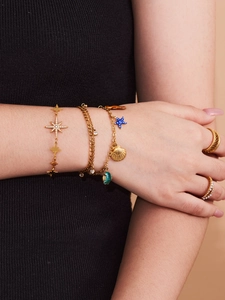 Detail von Goldstern- und Ozeanarmbändern mit Muscheln und Perlen am Handgelenk