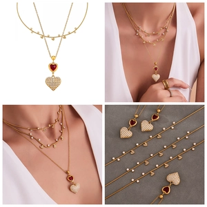 Dettaglio macro della collana dorata con pietra rossa e ciondoli a cuore in cristallo