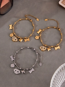 Macro detail of dog-themed stainless steel bracelets with sparkling paw and bone charms