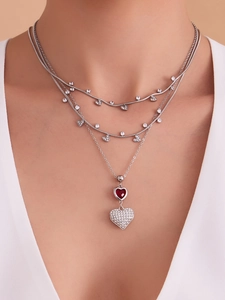 Dettaglio della collana argentata a strati con cuore rosso e zirconi micro-incastonati