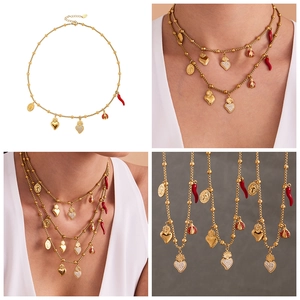 Détail du collier à perles dorées avec pendentifs cœur, piment rouge et coccinelle