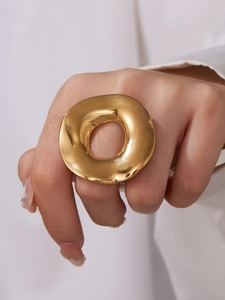 Close-up of chunky irregular gold donut ring with mirror polished finish on finger