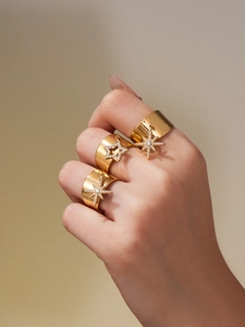 Close-up of gold plated wide rings with sparkling star charms and inset cubic zirconia