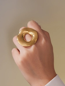 Macro detail of wide gold irregular ring showing polished mirror finish on the finger