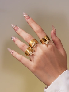 Detail of 18k gold plated stainless steel wide rings with zircon star charms on a hand