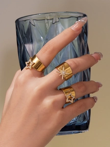 Detail of 18k gold plated wide band rings with star charms and sparkling zircon stones