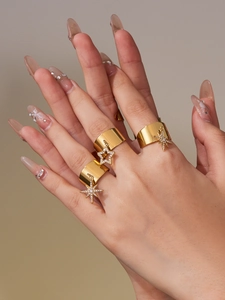 Detail of wide gold plated rings with star charms and sparkling cubic zirconia stones